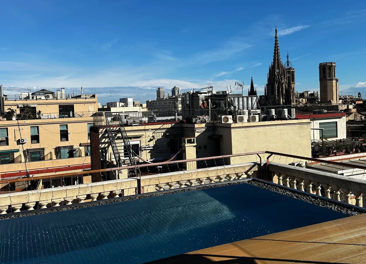Rooftop pool overlooking rooftops, a gothic spire, and a bell tower