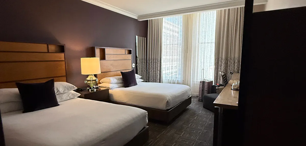 Hotel room with two beds, wood headboards, and a city window