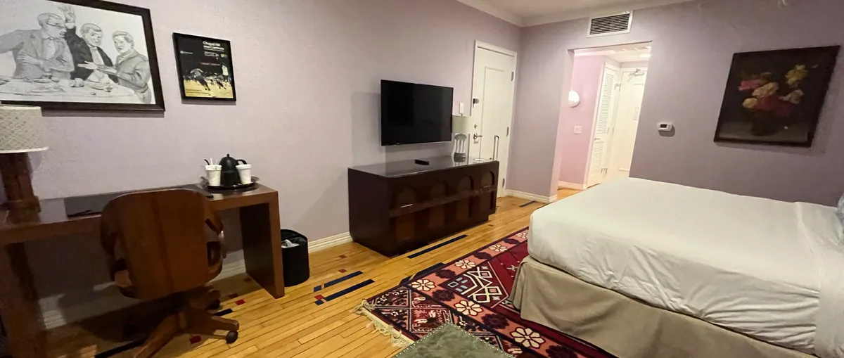 Hotel room with a bed, wooden desk, and wall-mounted television