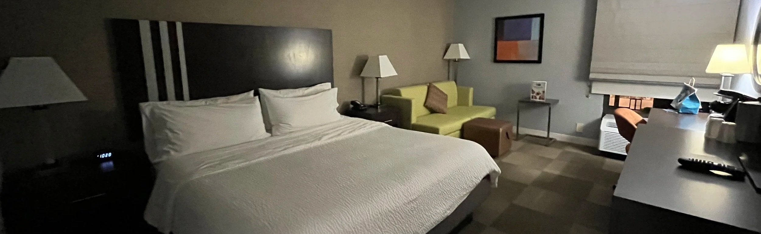 Hotel room with a large bed, lime sofa, and work desk