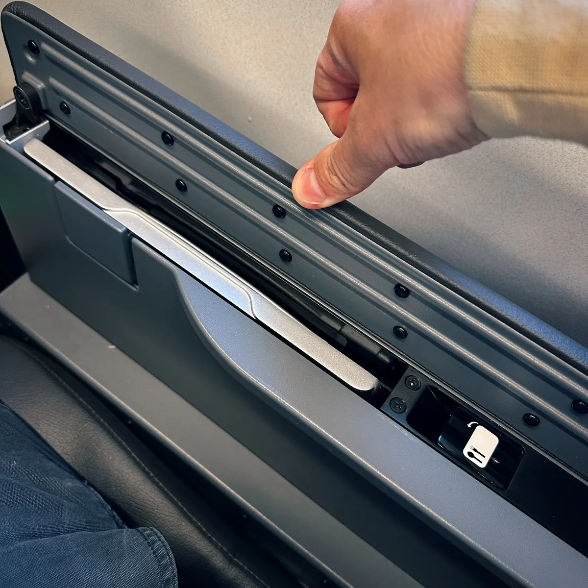 Hand pointing at a sliding tray in an airplane armrest