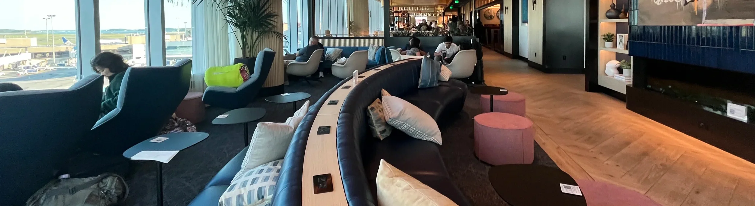 Curved sofa and armchairs in a lounge beside airport windows