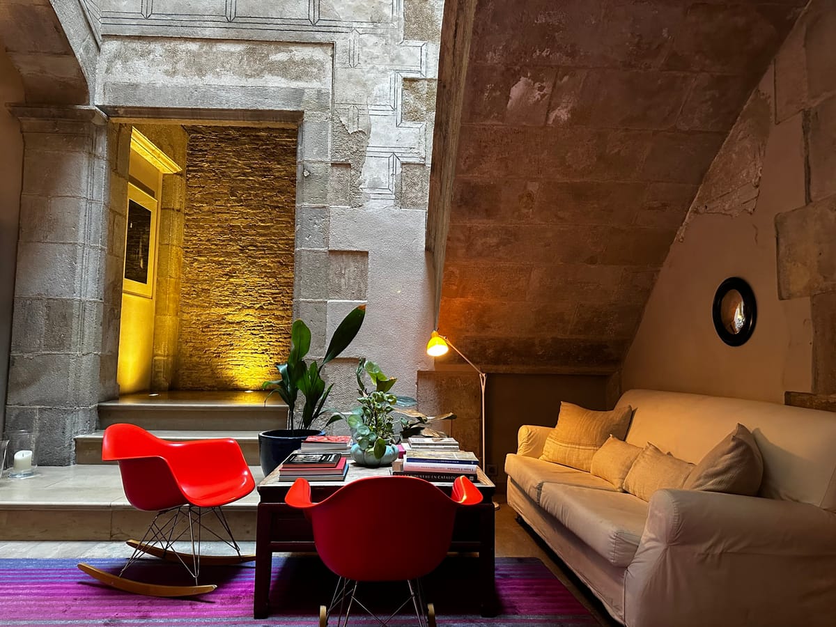 Hotel Neri lobby with stone walls, red chairs, and a sofa