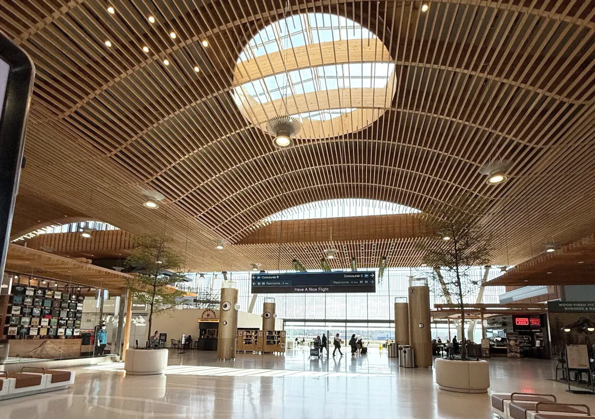 Airport concourse under a curved wooden ceiling and skylight