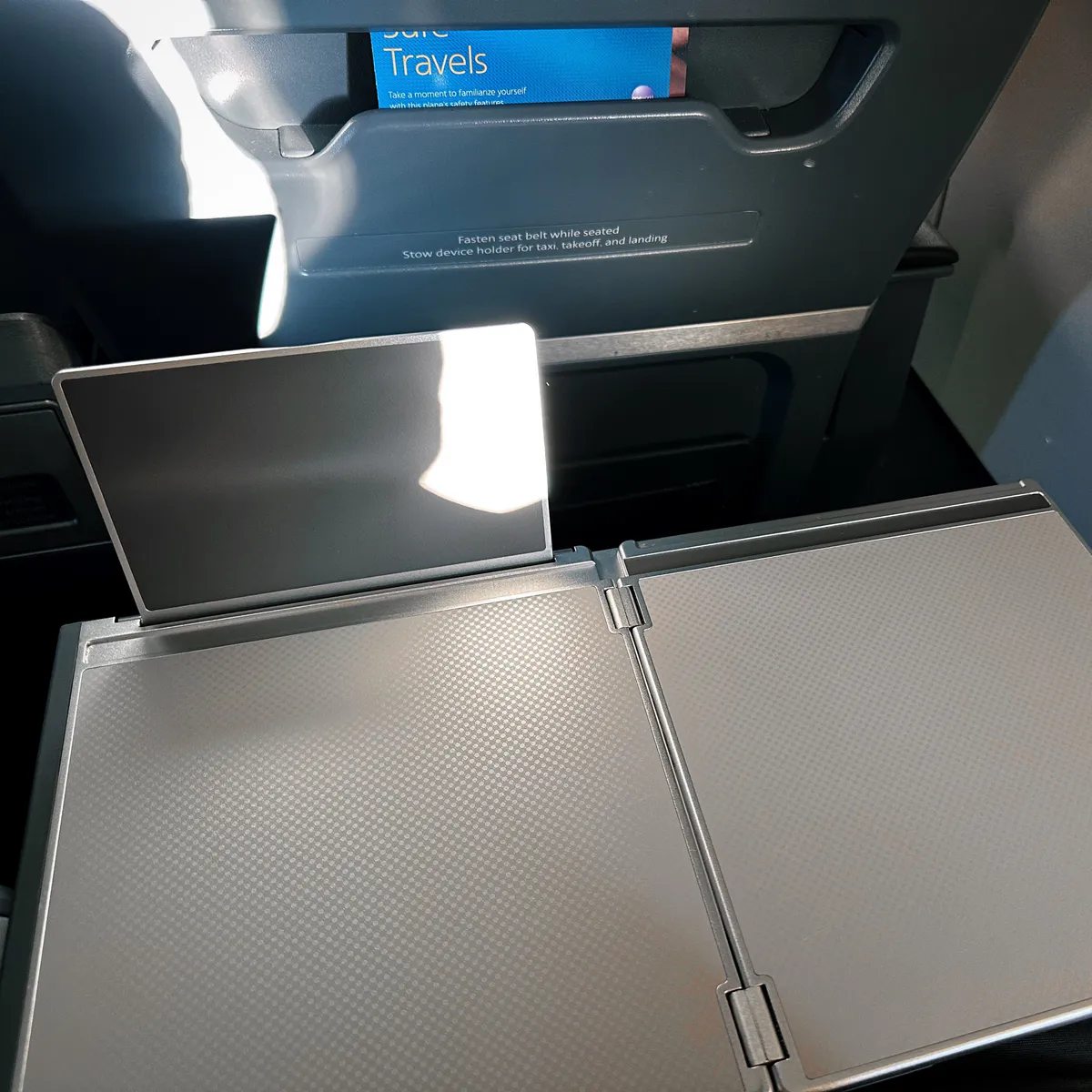Open airplane tray table with a raised device holder screen