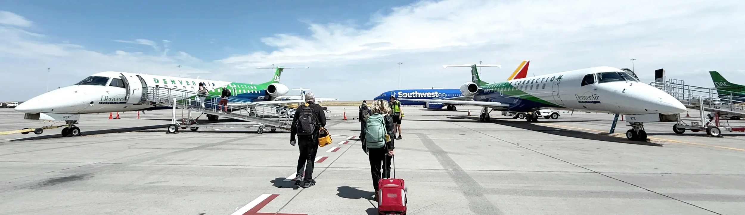Travelers crossing a tarmac between Denver Air and Southwest jets