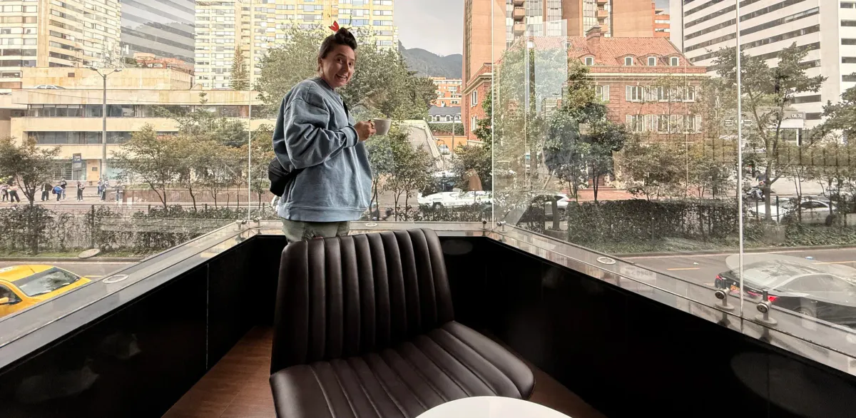 Person with coffee beside a leather bench in the Hilton Bogota lounge