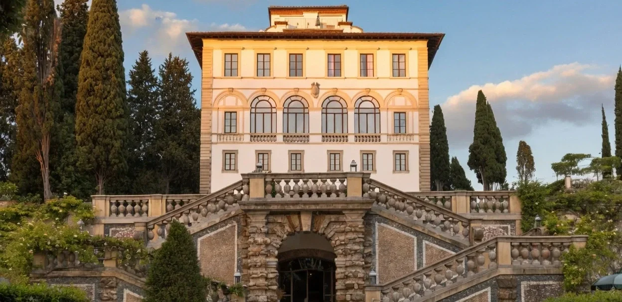 Pale villa above a stone staircase lined with cypress trees