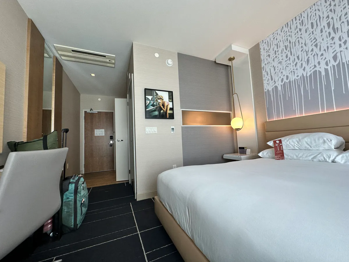Luggage beside a chair near the door, with the king bed on the right