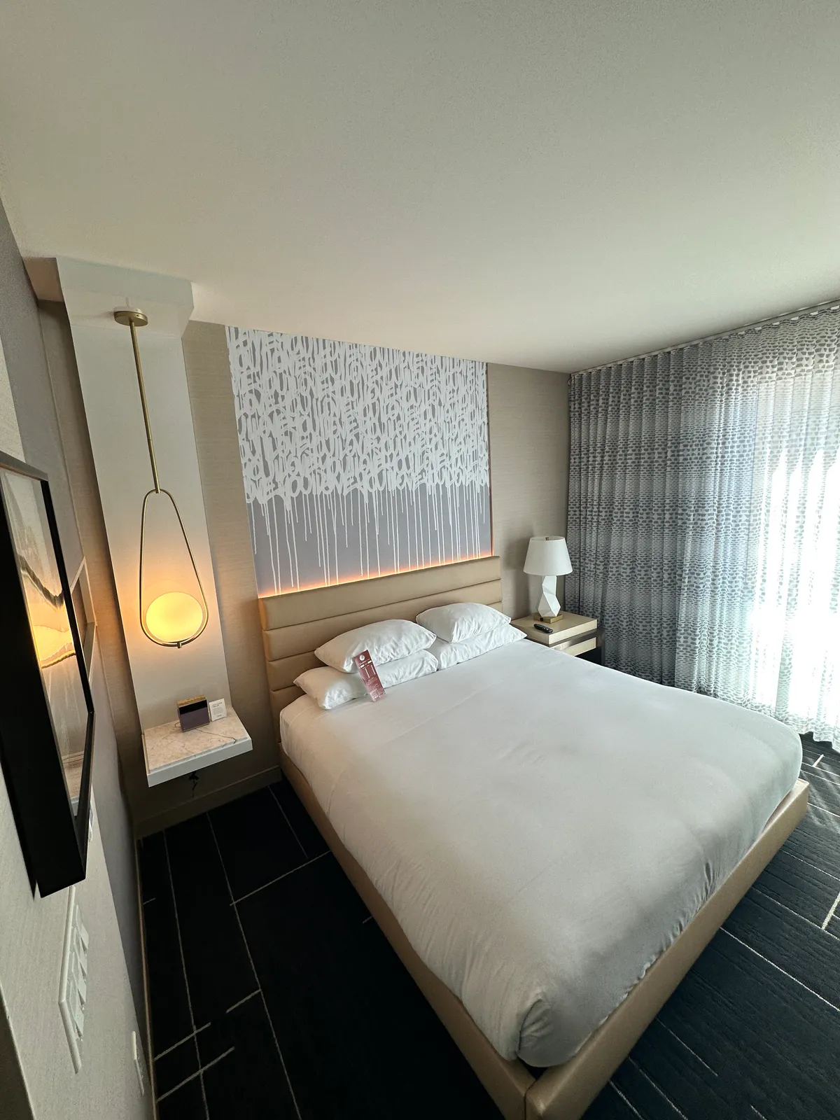 Side angle of the king bed with a pendant light and television edge