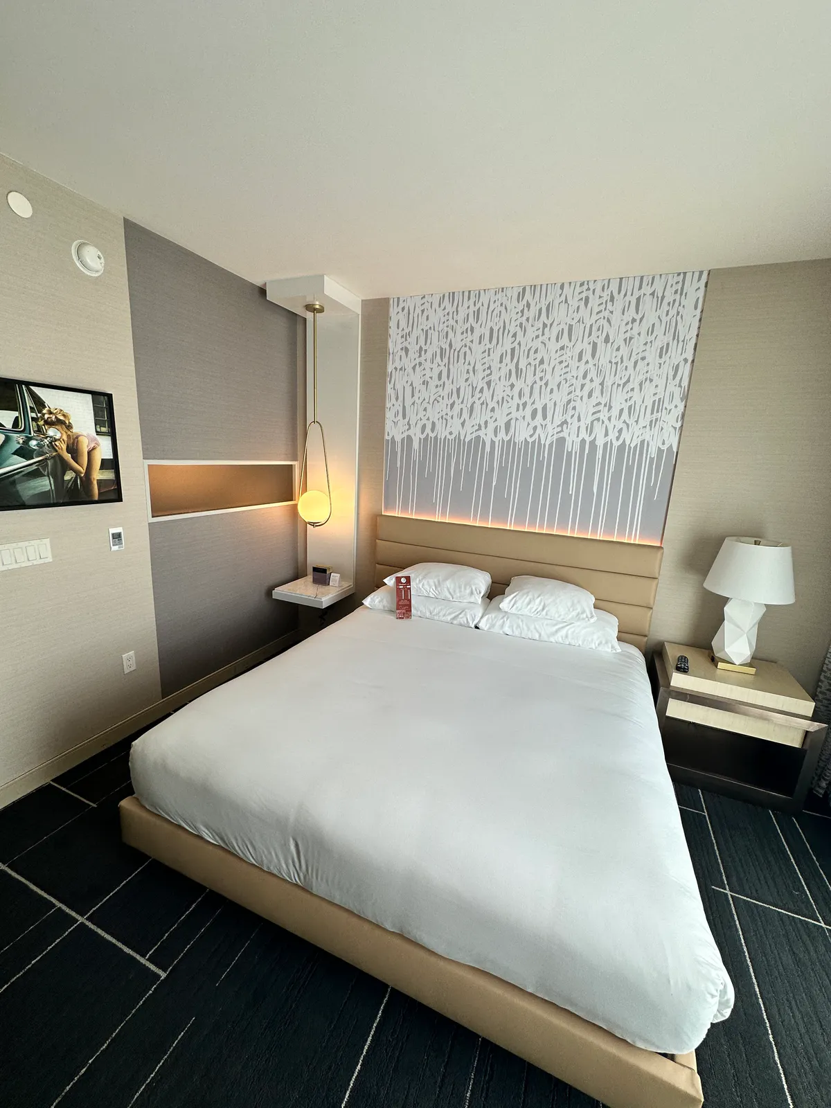 King bed facing a dripping art panel, with the television on the left wall