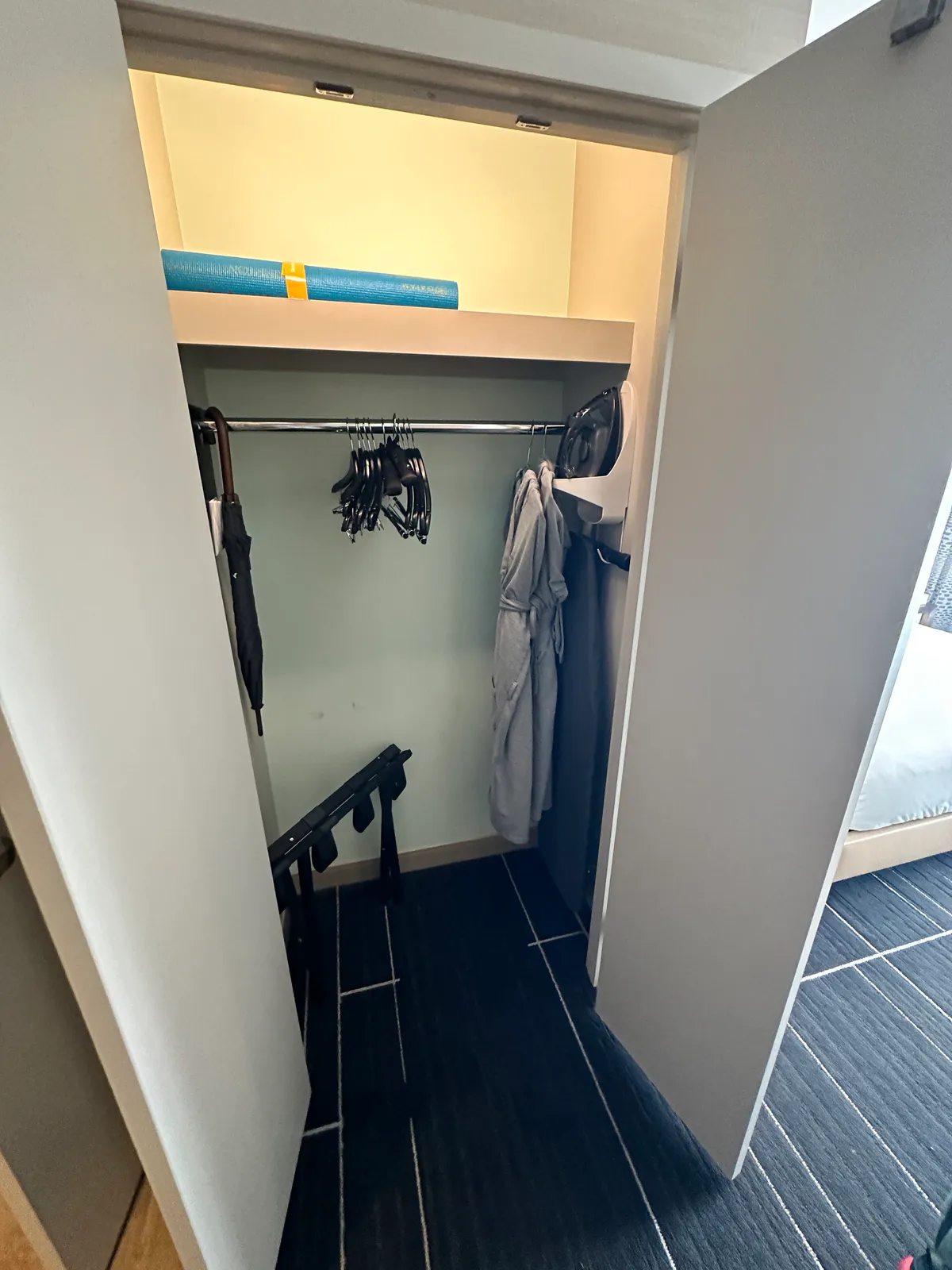 Open closet with robes, hangers, an umbrella, a rack, and a rolled mat