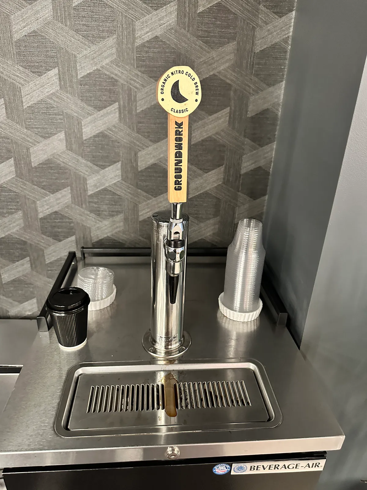 Groundwork nitro cold brew tap with plastic cups on a steel counter