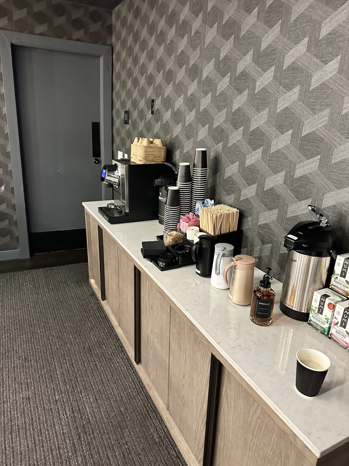 Coffee station with an espresso machine, carafes, syrup, and boxed teas