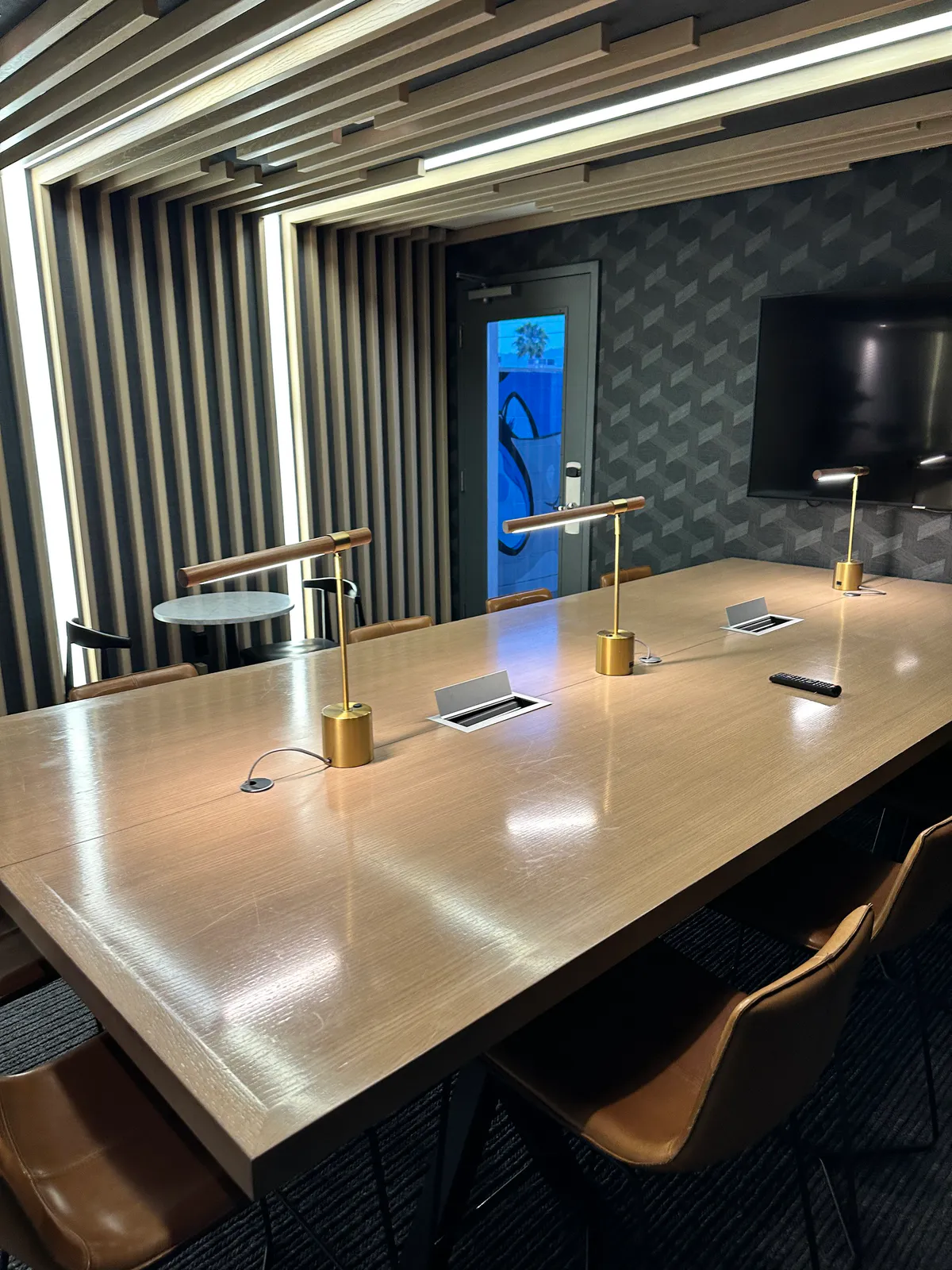 Long wood table with brass desk lamps and brown leather chairs
