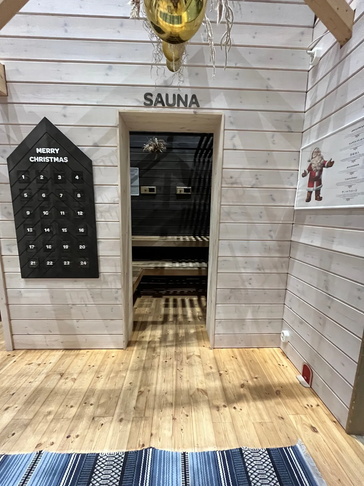 A pale wood cabin interior with a sauna doorway and a Christmas advent calendar