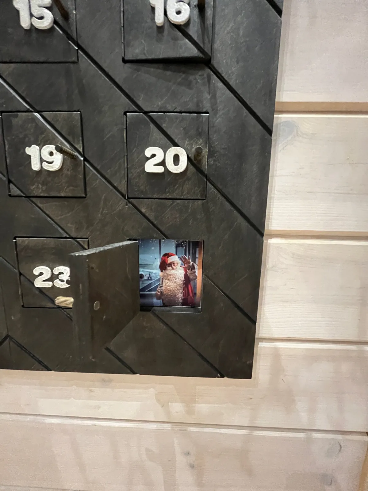 Close-up of a dark advent calendar with one door open on a Santa photo