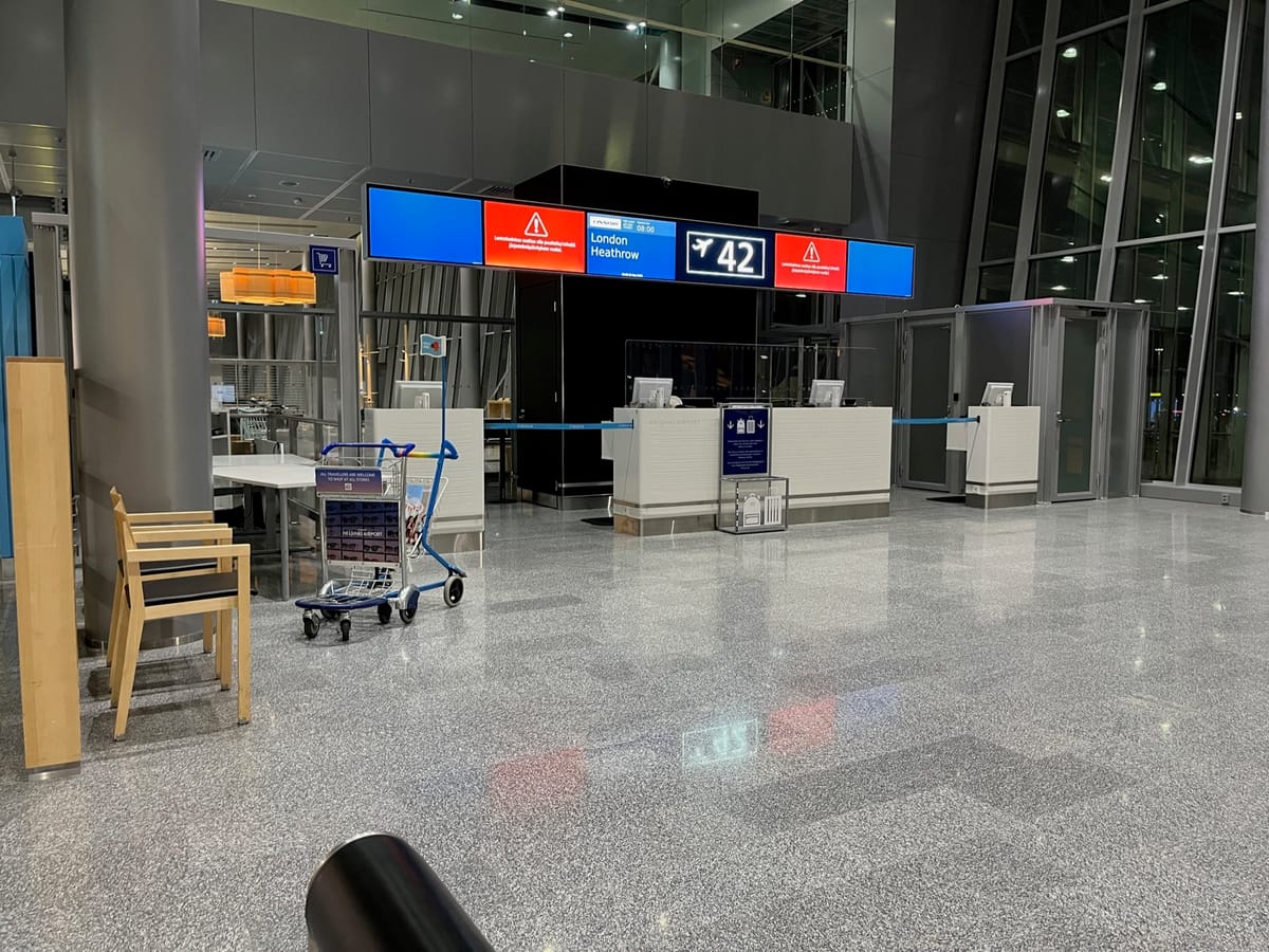 An empty gate area signed London Heathrow and 42, with desks and a luggage cart