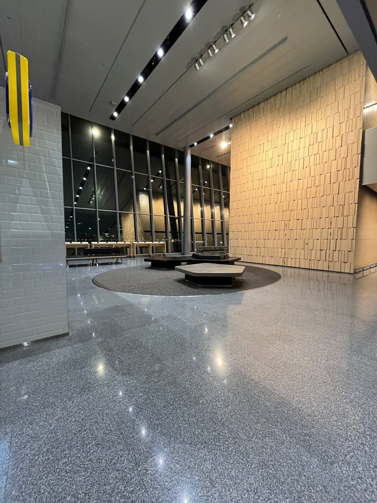 Hexagonal benches on a circular rug between night windows and a wood-block wall