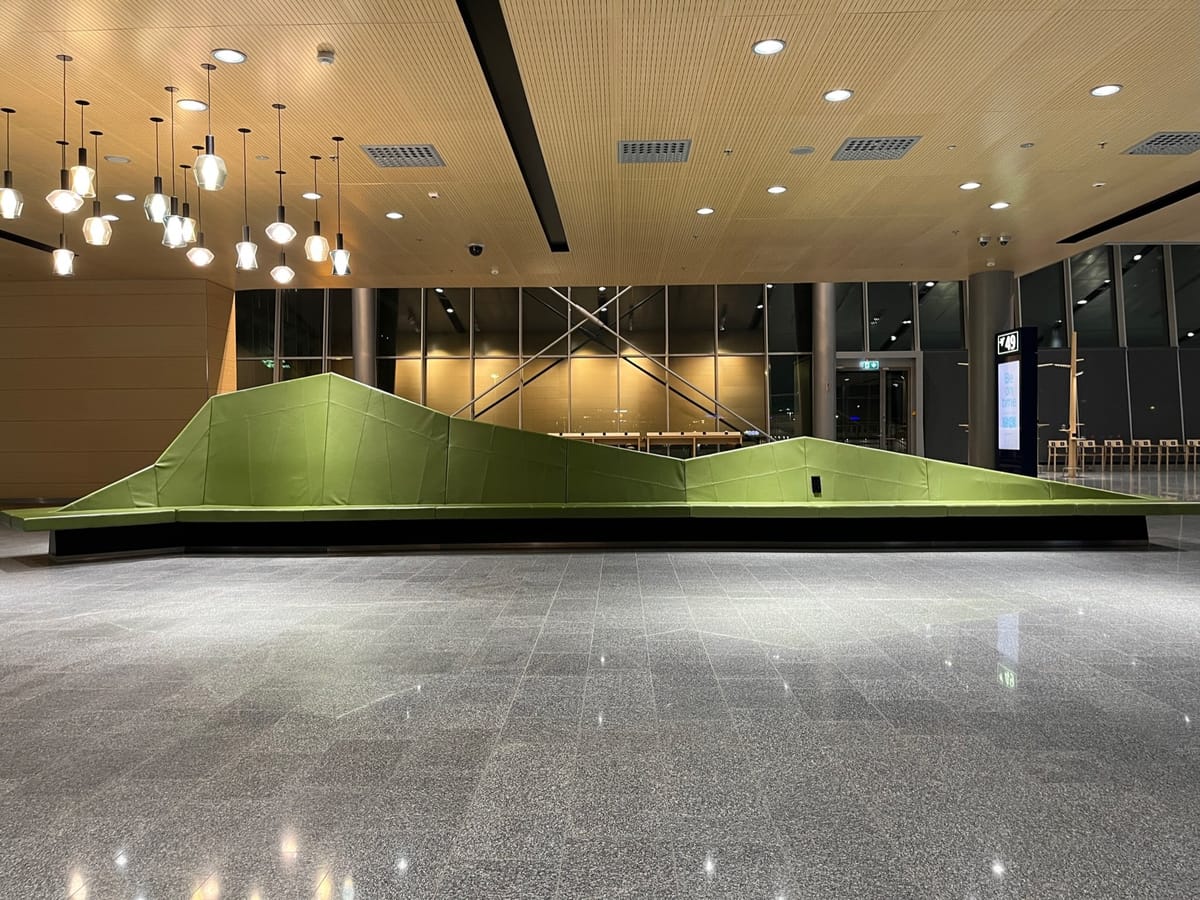 A long lime-green sofa shaped like a mountain range under hanging pendant lights