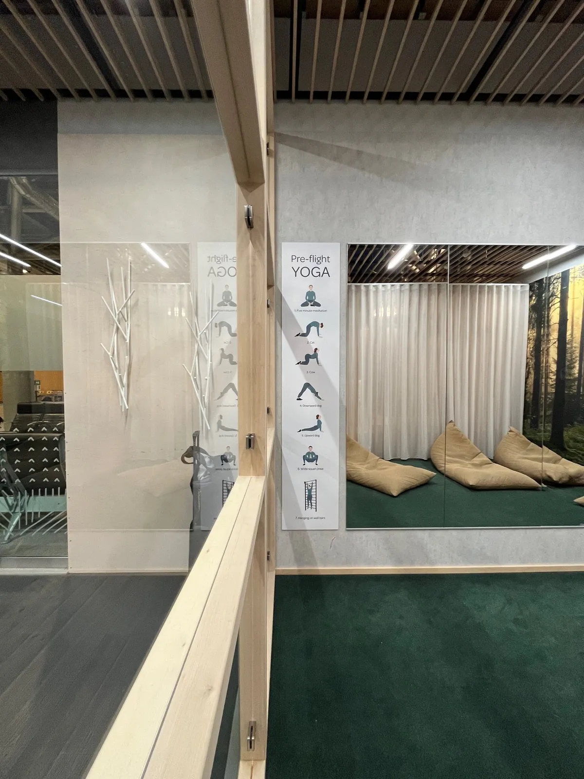 A Pre-flight Yoga poster beside beige beanbags on a green carpet