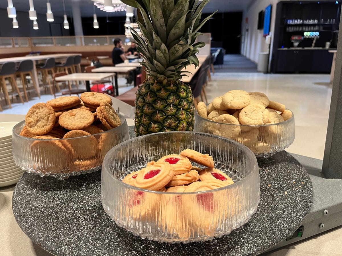 Glass bowls of cookies arranged around a pineapple on a speckled tray