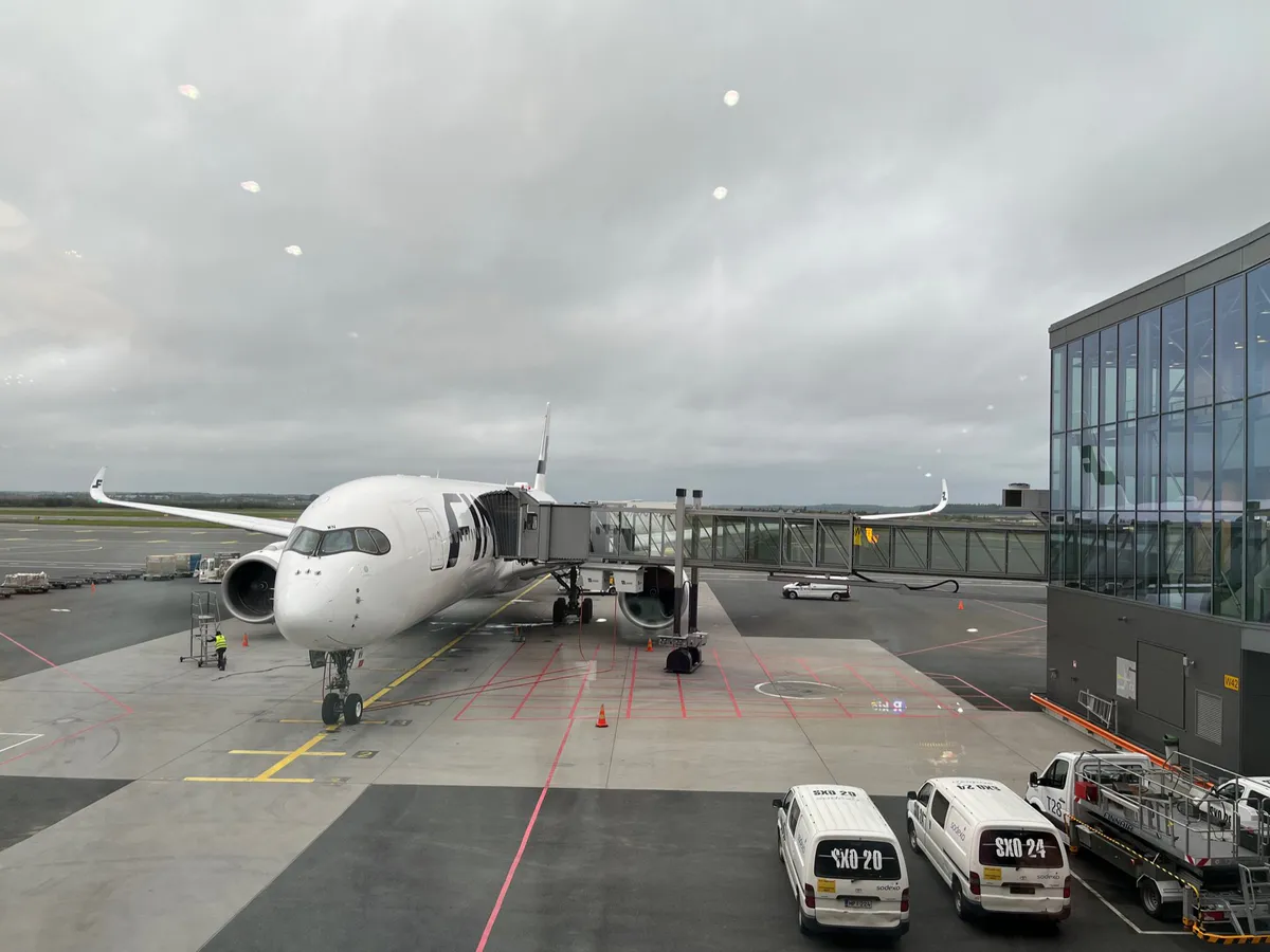 A Finnair jet parked at a jet bridge on a cloudy apron