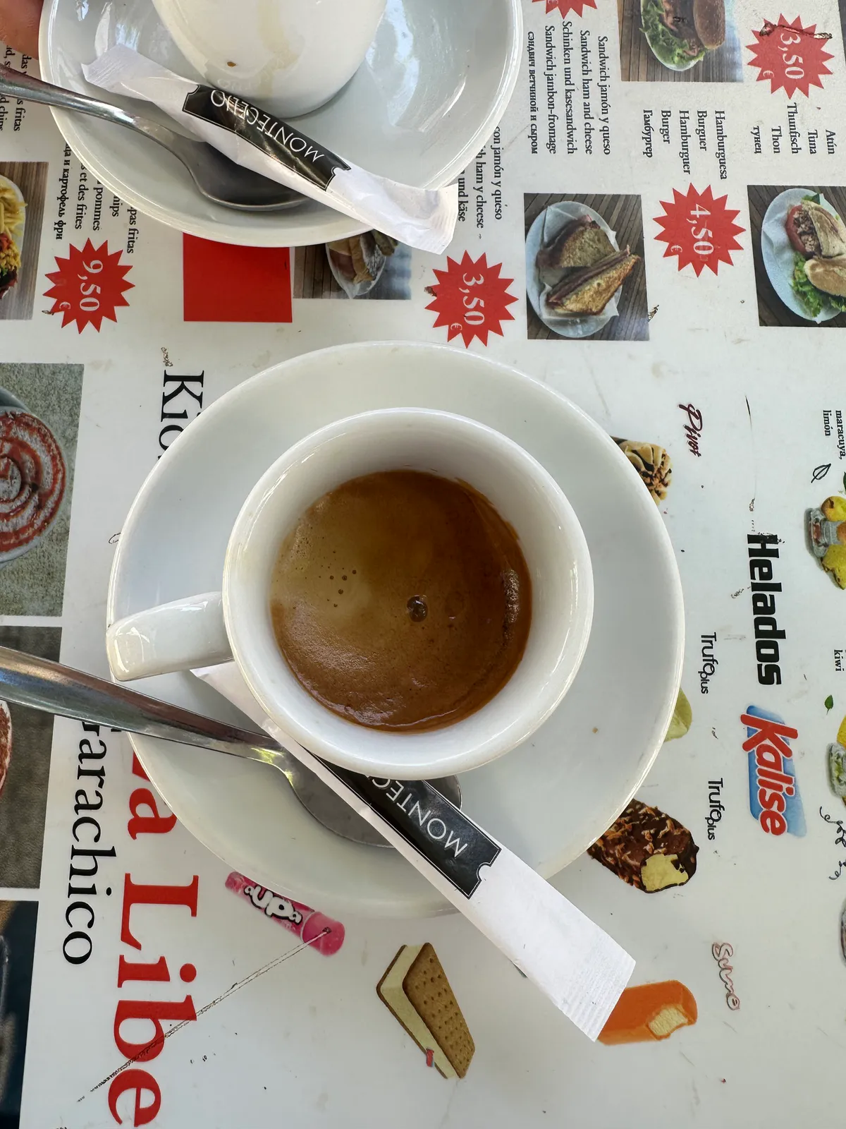 A cup of espresso on a printed cafe menu showing ice cream and sandwiches.
