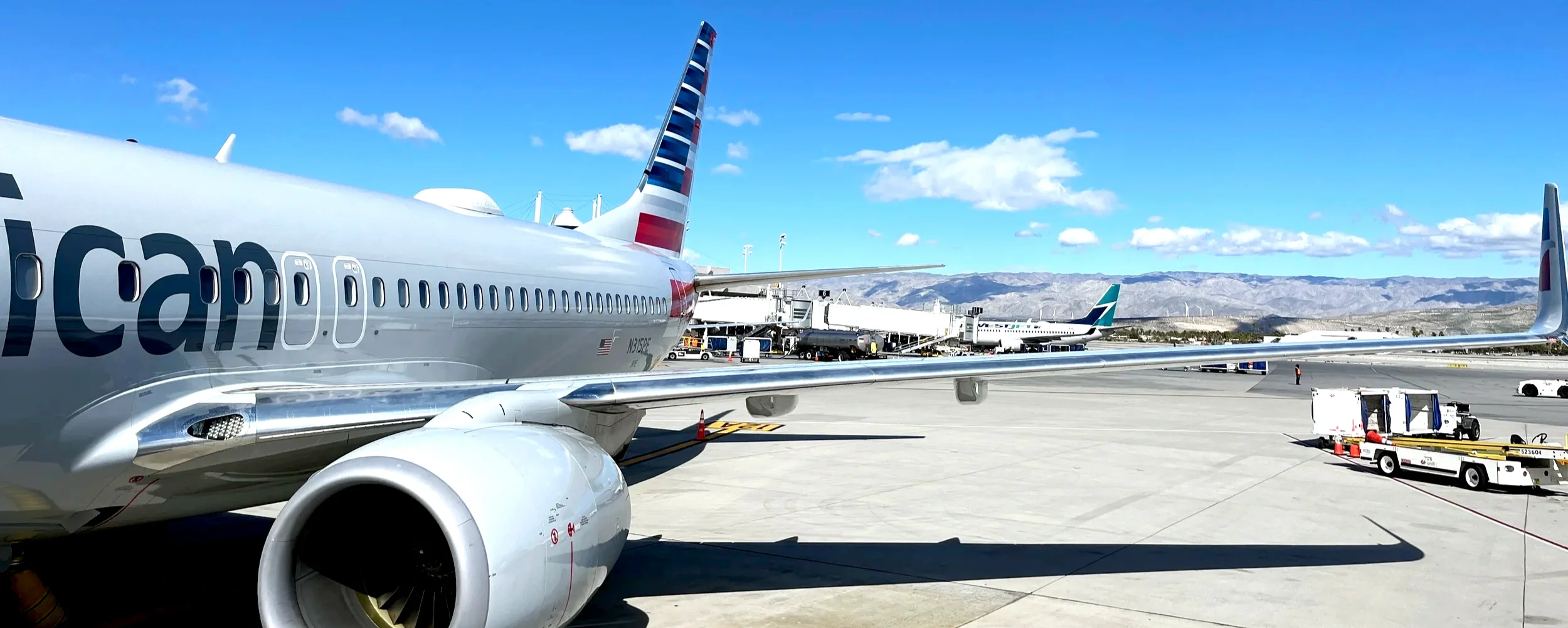 American Airlines jet on the tarmac with mountains beyond the wing