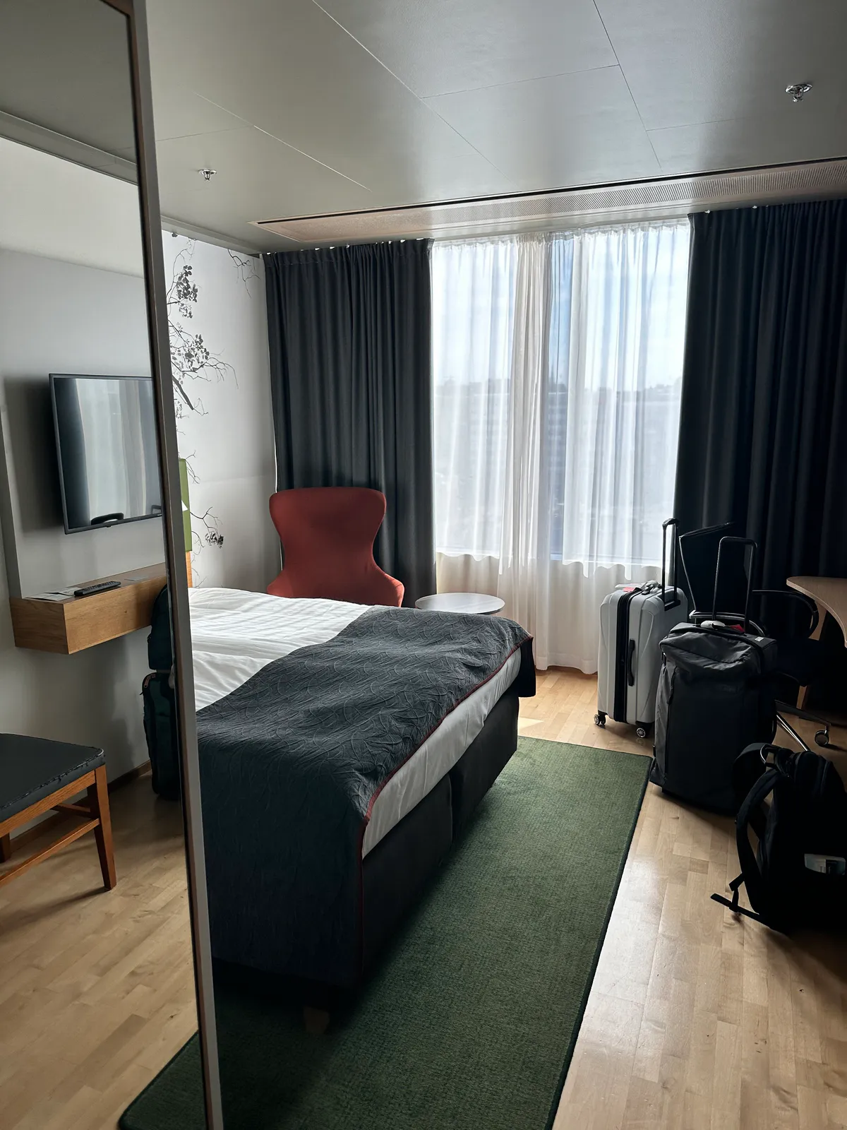 Holiday Inn Helsinki room with a bed, red chair, and luggage