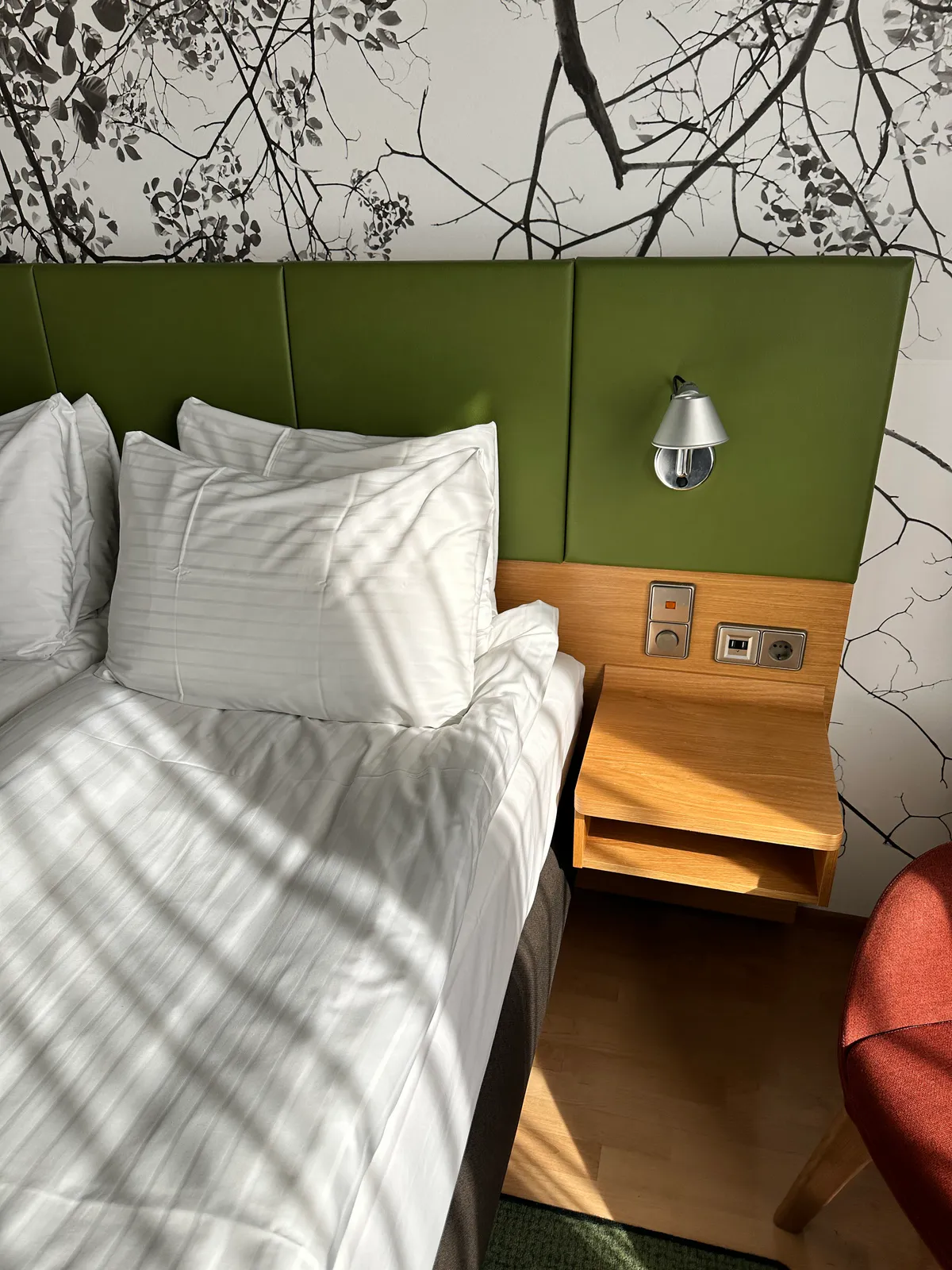 Holiday Inn Helsinki pillows, green headboard, and a nightstand