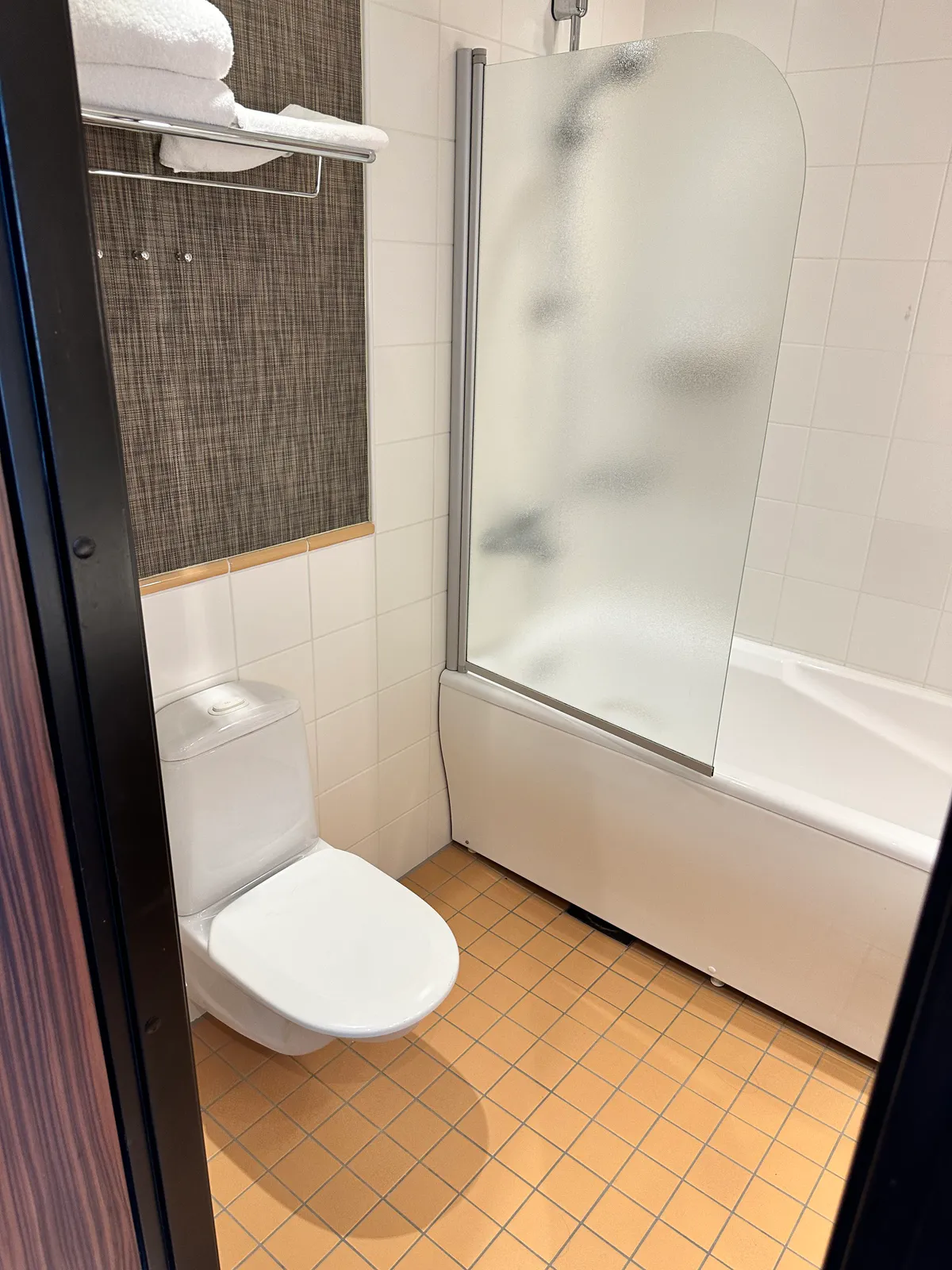 Holiday Inn Helsinki bathroom with a toilet, tub, and shower screen