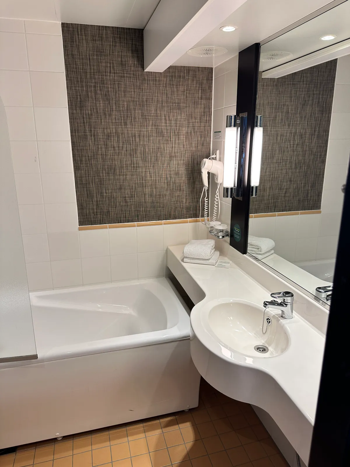 Holiday Inn Helsinki sink, hairdryer, and towels by the tub