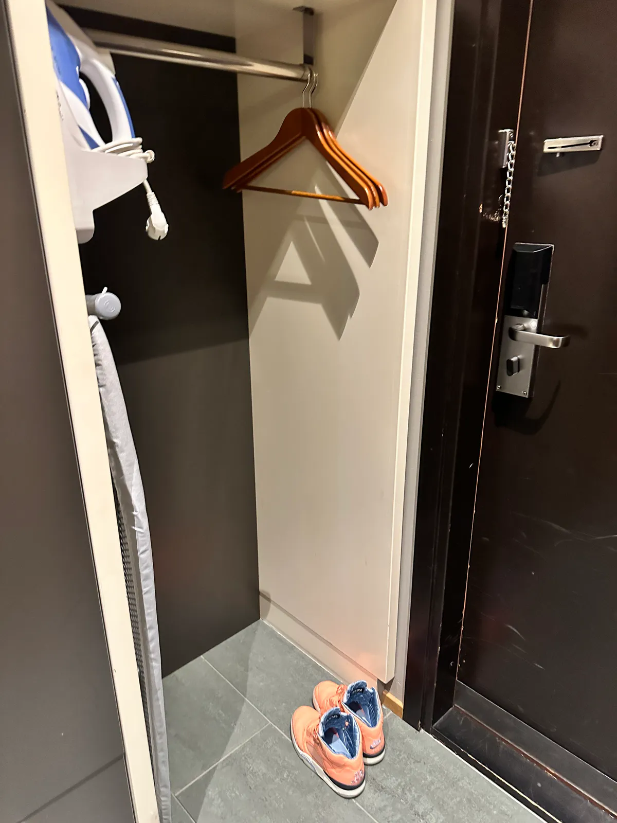 Holiday Inn Helsinki closet with hangers, an iron, and orange shoes