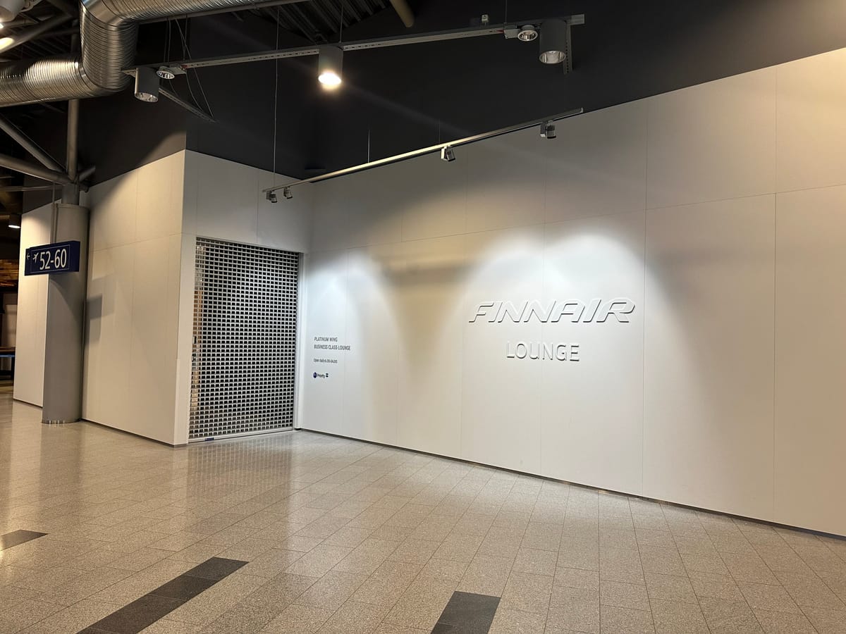 The Finnair Lounge name on a white wall beside a closed metal grille
