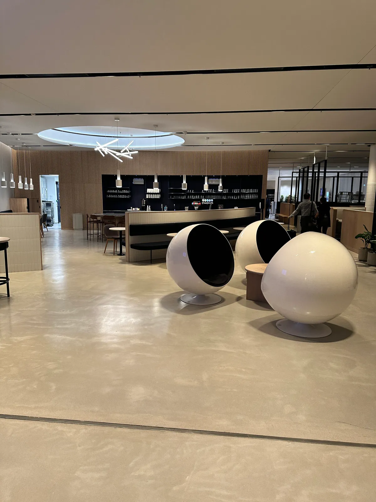 White spherical pod chairs facing a lounge bar backed by a wood-slat wall