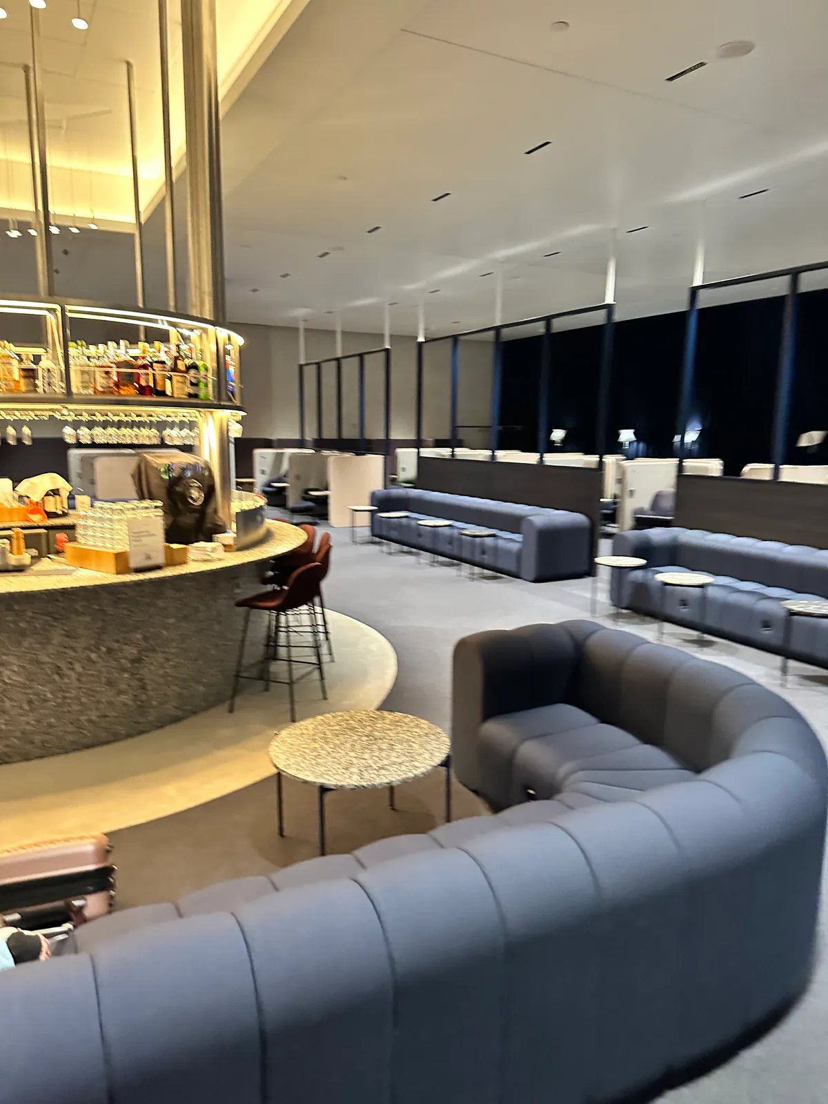 Blue curved sofas filling a dim lounge beside a granite bar and dark windows