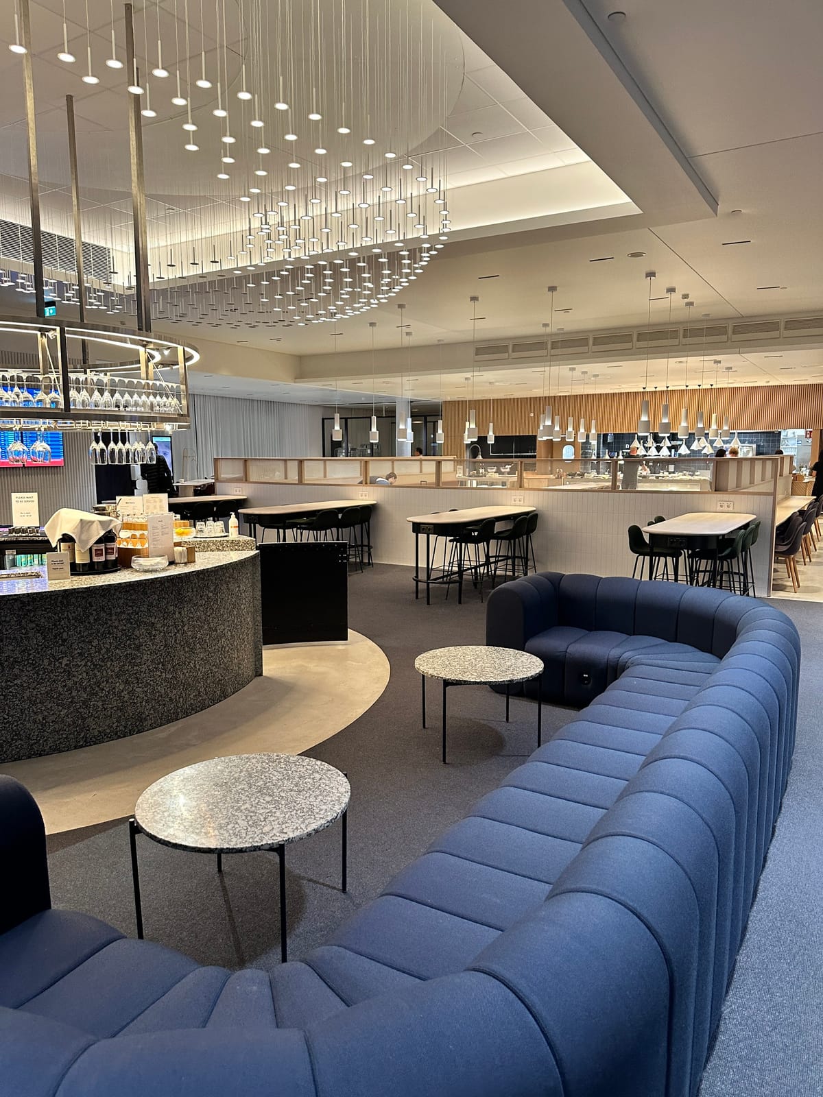 A curved blue sofa under a cloud of hanging lights near the lounge buffet