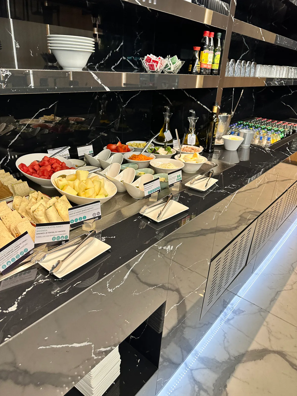 Lounge buffet of sandwiches, cut fruit, salad bowls, and condiment bottles
