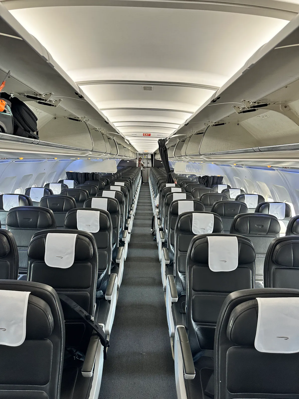 British Airways cabin looking aft, with black leather seats and white headrest covers