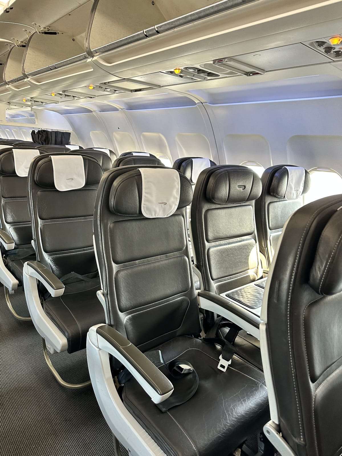 Club Europe seats with black leather cushions, white headrest covers, and a center table