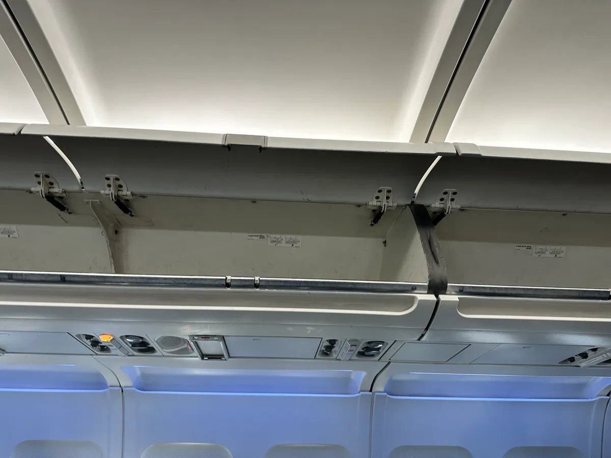 Open empty overhead bins above the cabin with reading lights and air vents