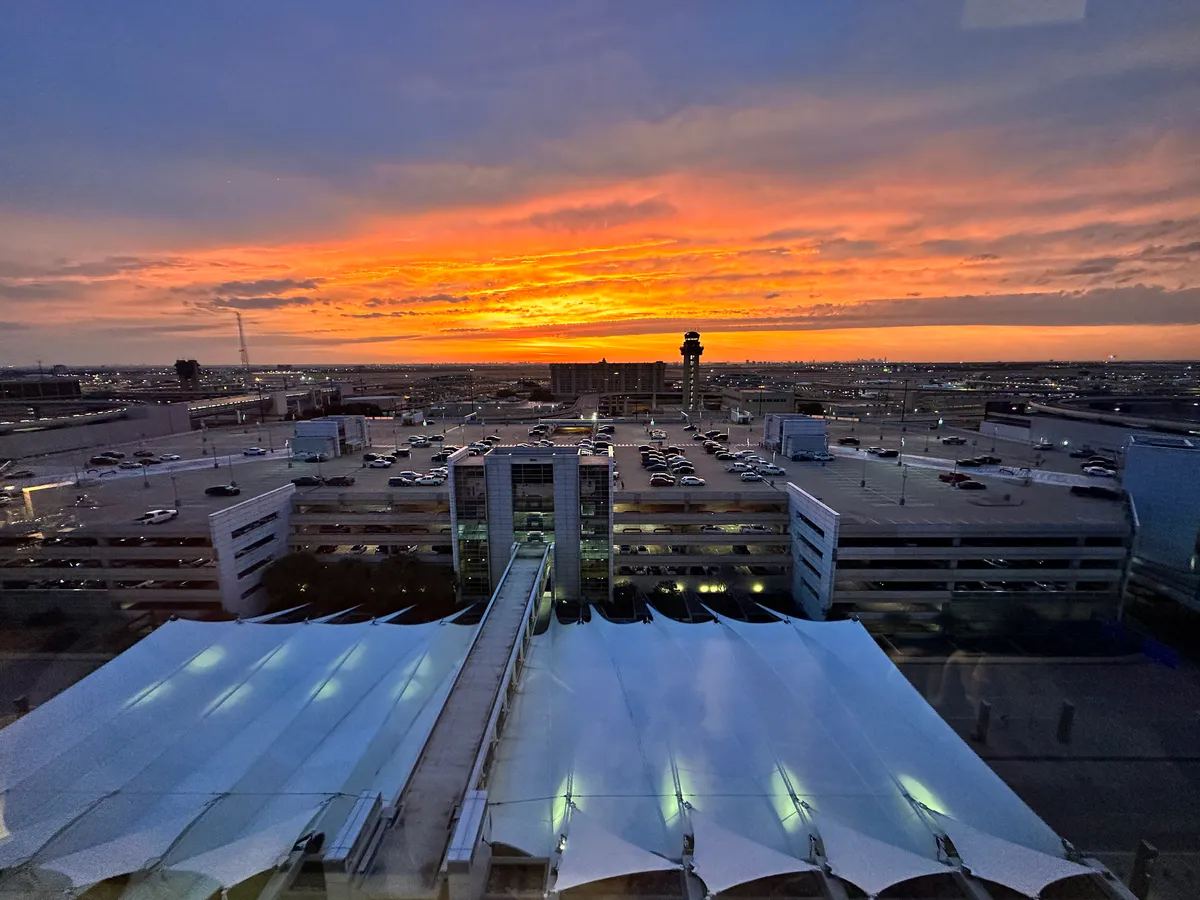 Sunset from the Grand Hyatt DFW over airport canopies and a control tower