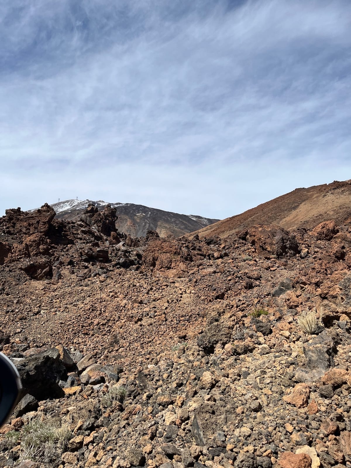 Loose volcanic rubble sloping toward a snow-dusted ridge under a pale sky