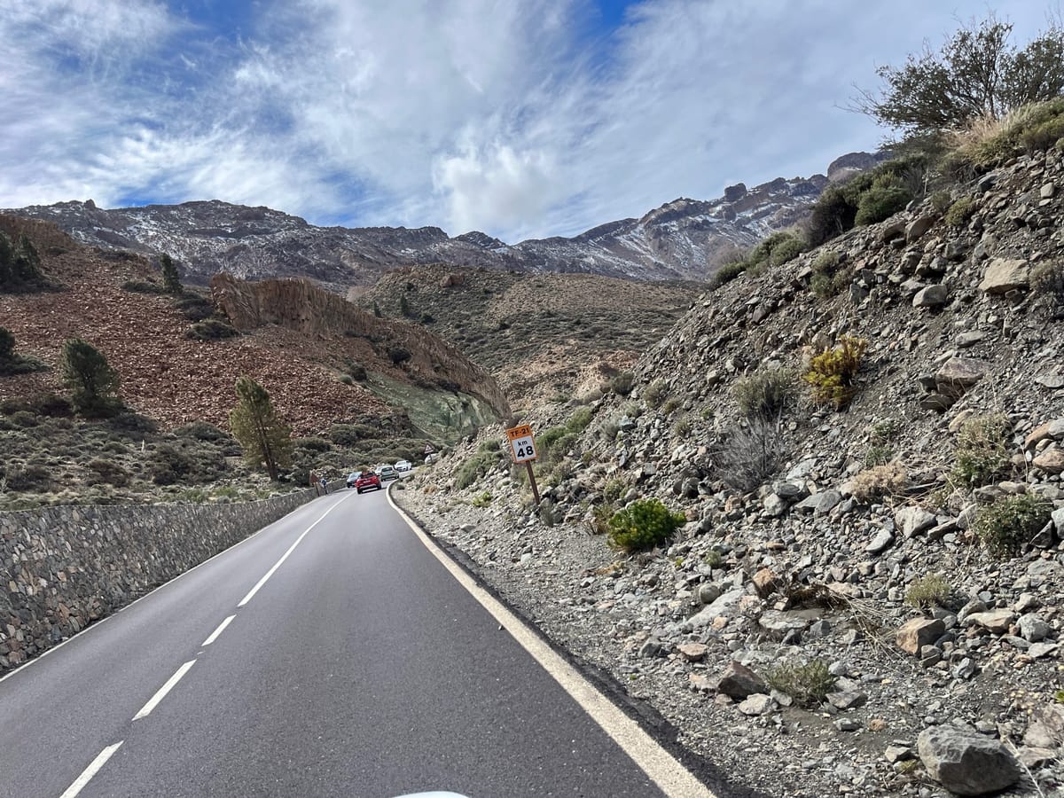 Winding mountain road with a 48 speed sign and snowy ridges ahead