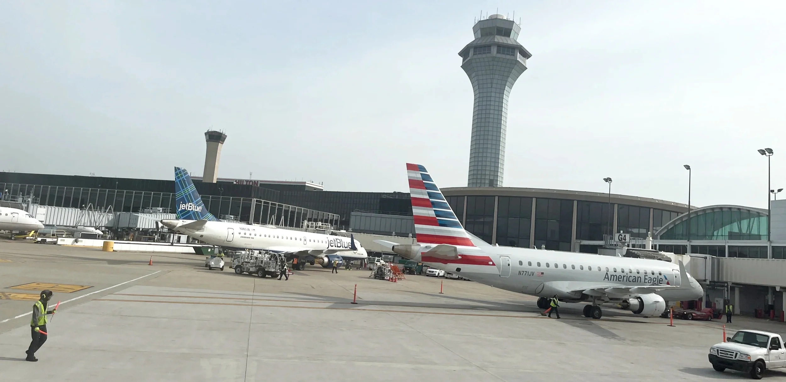 American Eagle and JetBlue jets parked near an airport control tower