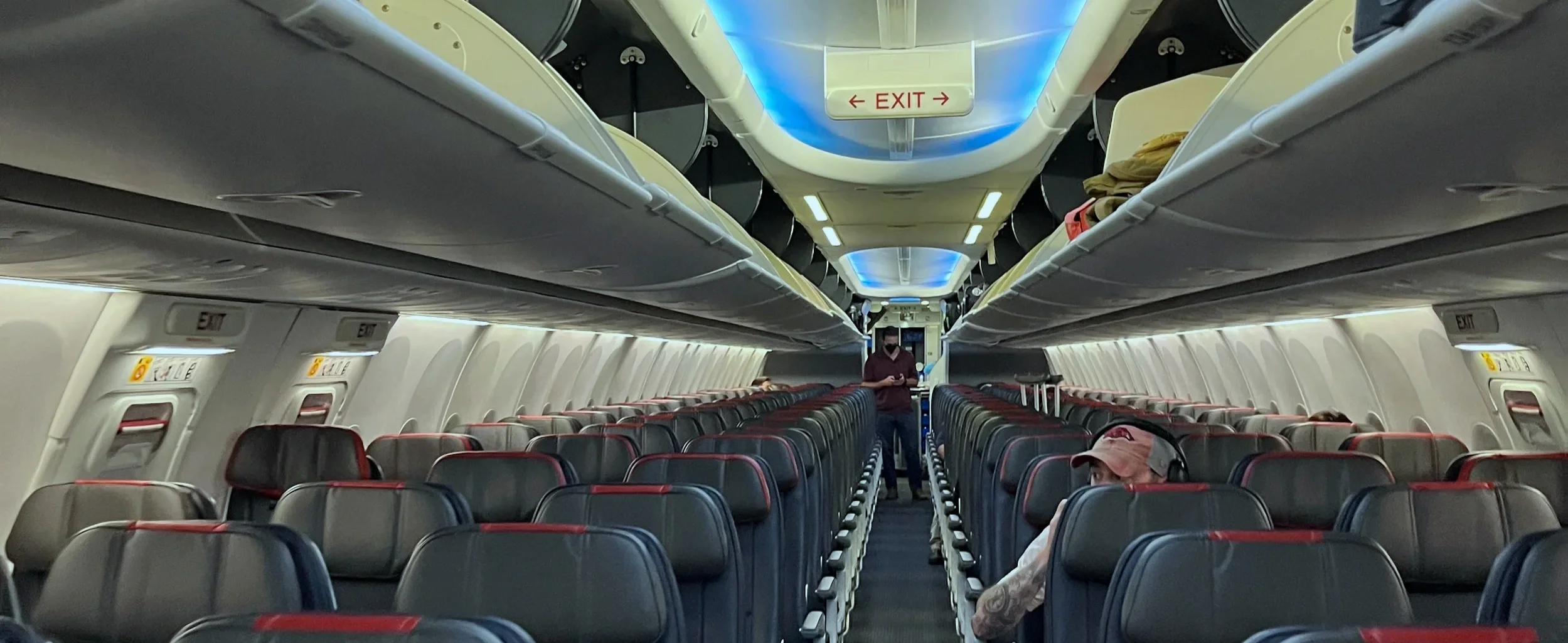Narrow cabin aisle with a flight attendant standing among the seats