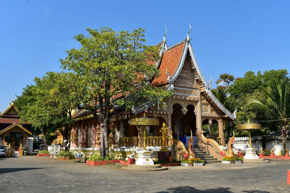 Ornate Thai temple with a red roof and golden serpent stair rails